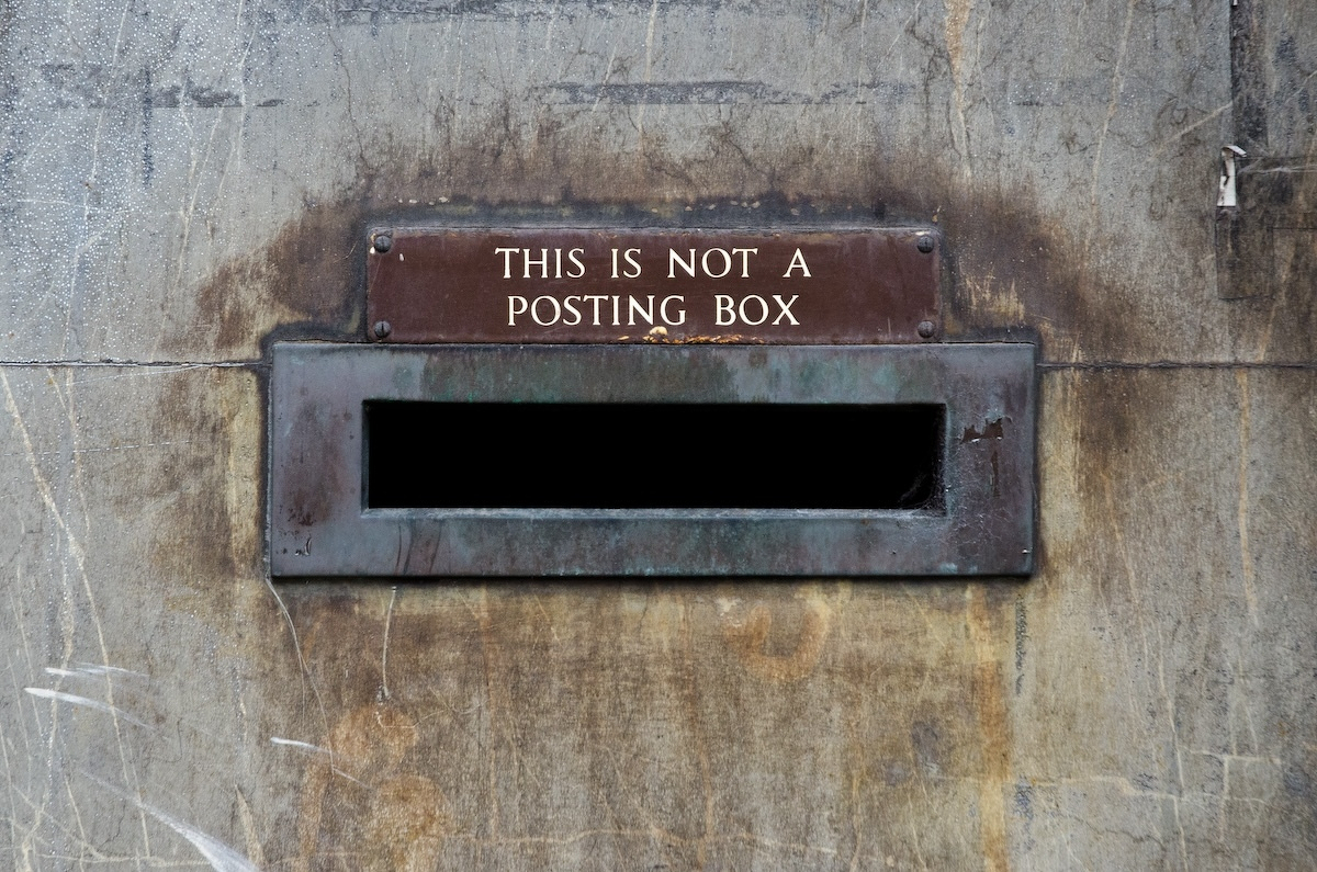 A letterbox slot in a wall. The sign above it says This is Not a Posting Box.